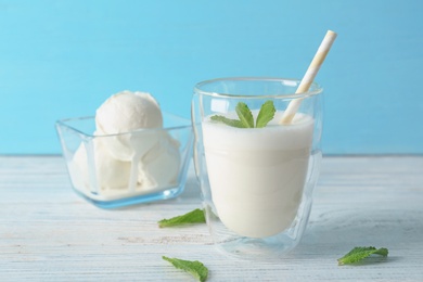 Photo of Glass with milk shake and tasty vanilla ice cream on wooden table