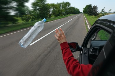 Photo of Driver throwing away plastic bottle from car window. Garbage on road