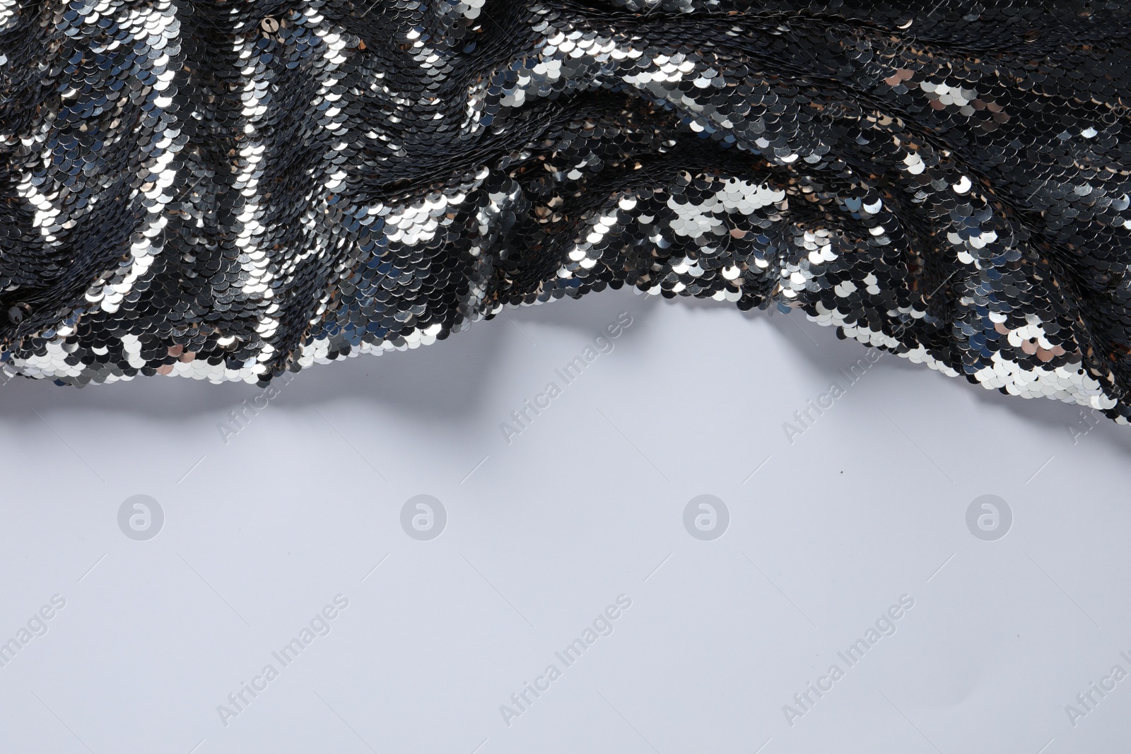 Photo of Beautiful bright sequin fabric on white background, top view. Space for text
