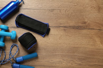 Photo of Blue weighting agents and sport equipment on wooden table, flat lay. Space for text