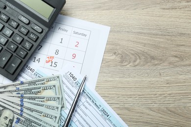 Photo of Tax day. Calendar with date reminder, documents, pen, calculator and dollar banknotes on wooden table, flat lay. Space for text