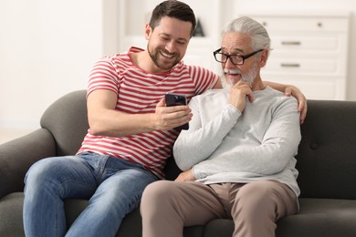 Happy son and his dad watching something on smartphone at home