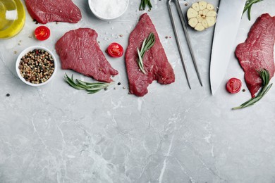 Fresh raw meat steaks and spices on light grey table, flat lay. Space for text