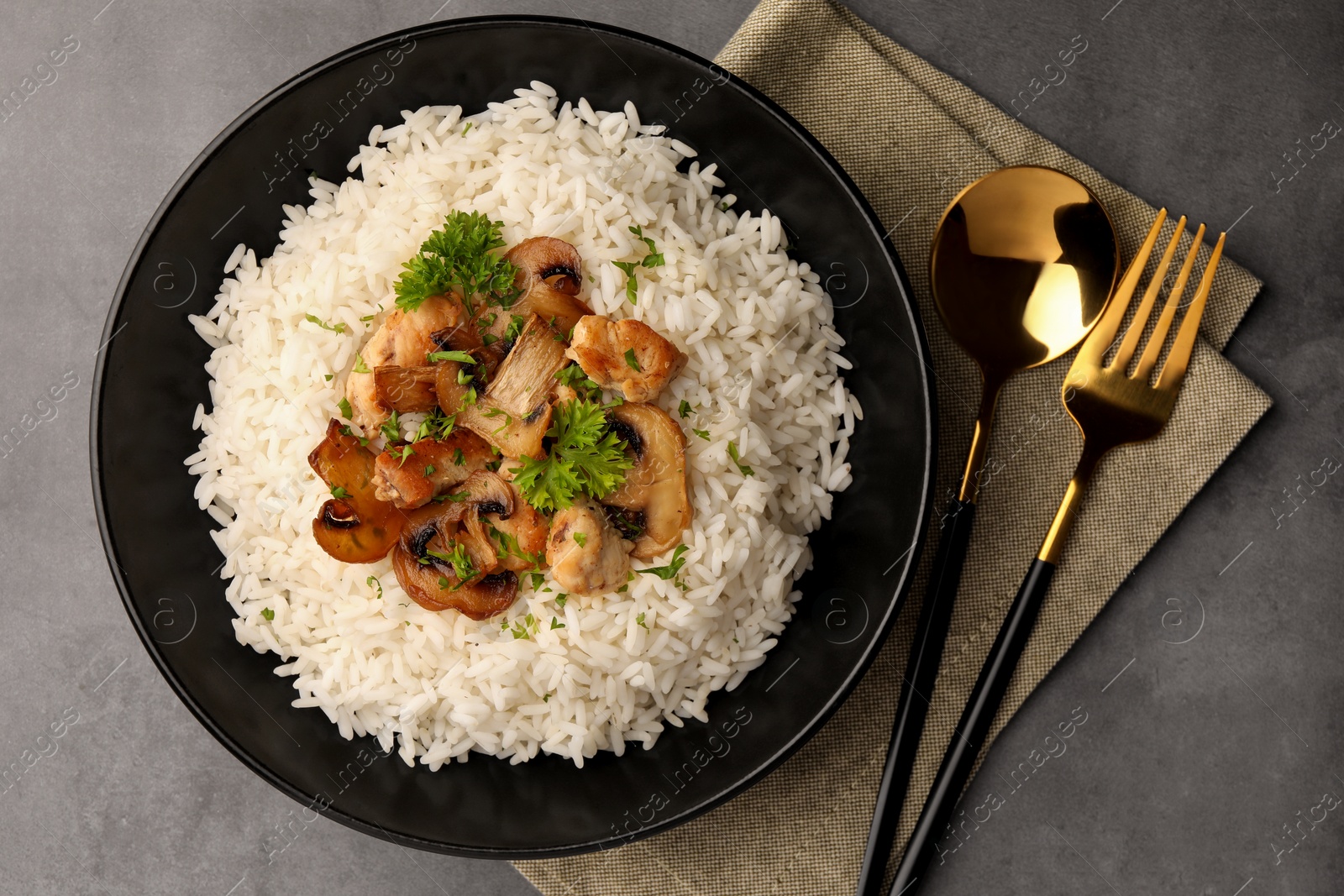 Photo of Delicious rice with parsley and mushrooms served on grey table, flat lay