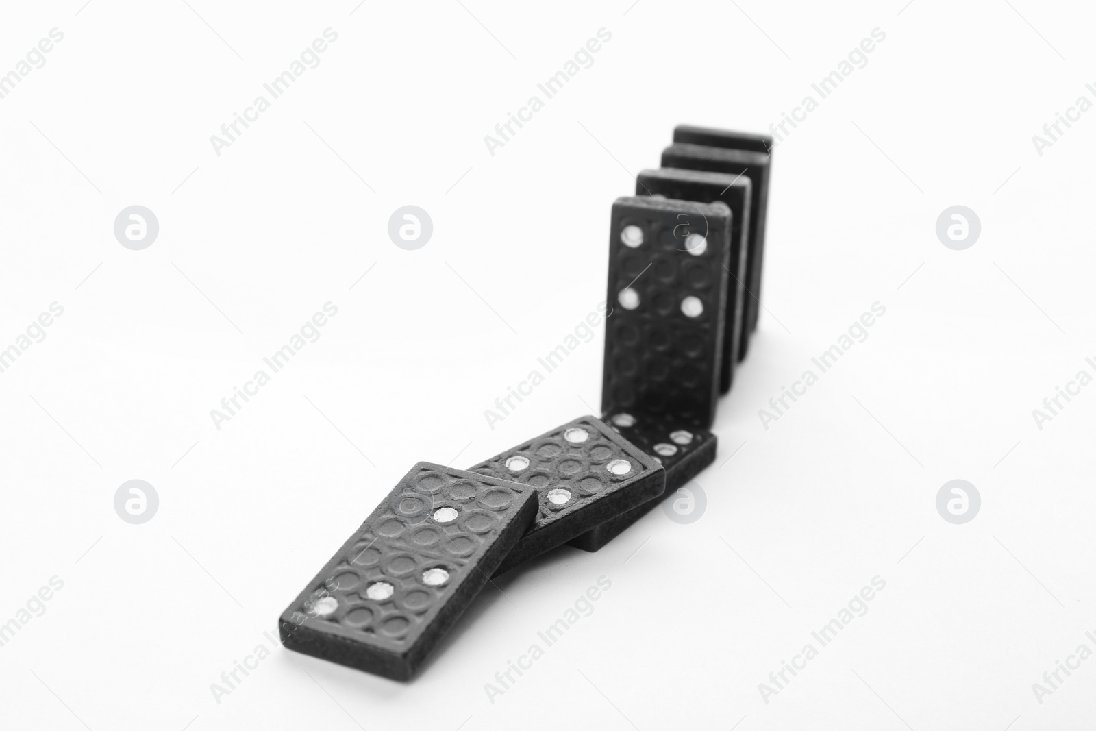 Photo of Black domino tiles falling on white background