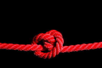 Photo of Red rope with knot on black background