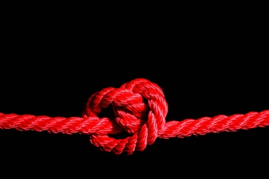 Red rope with knot on black background