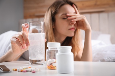 Photo of Woman taking medicine for hangover, focus on hand with glass