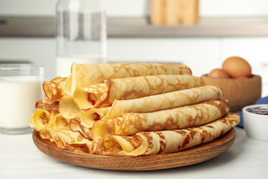Photo of Fresh thin pancakes on white wooden table
