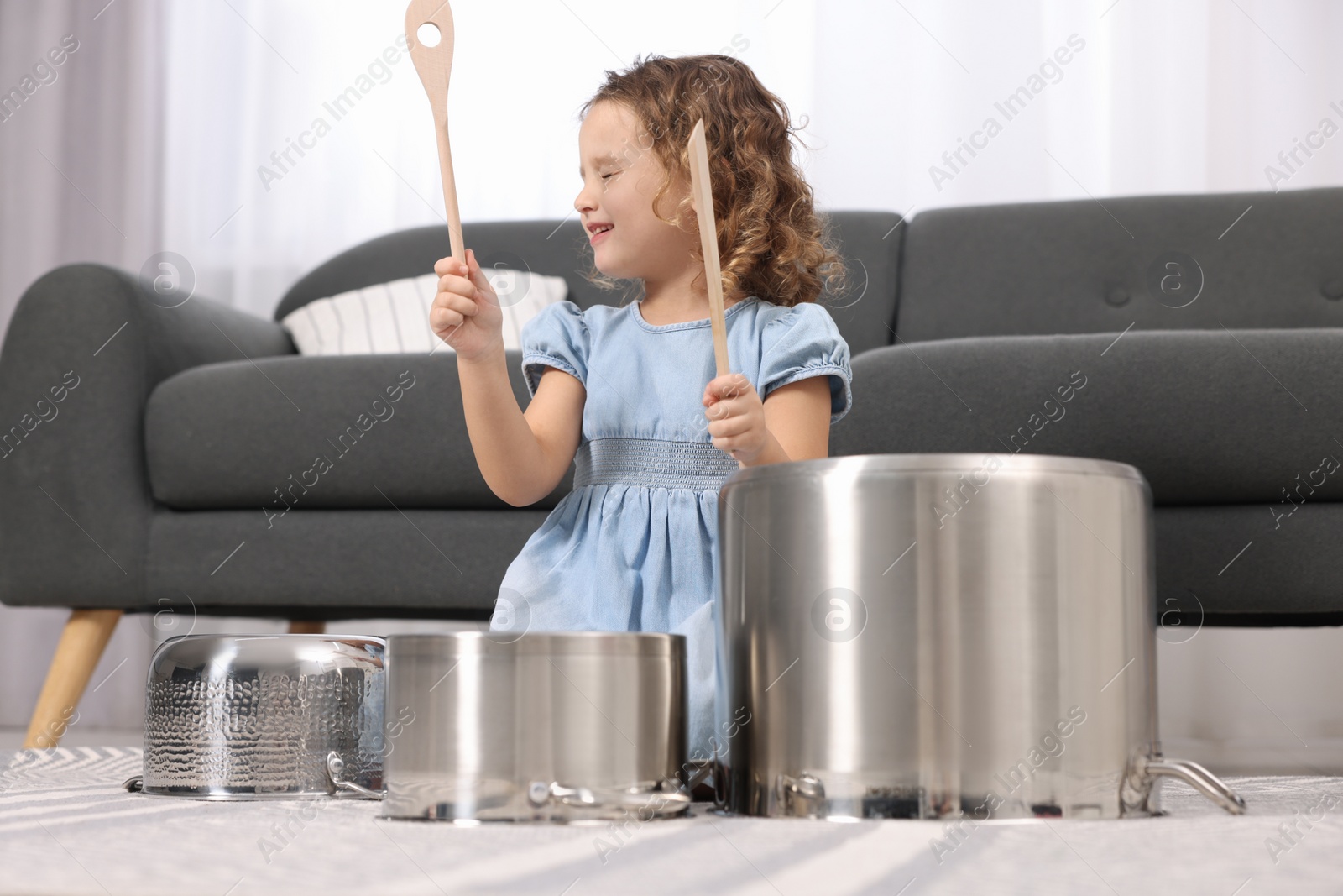 Photo of Little girl pretending to play drums on pots at home