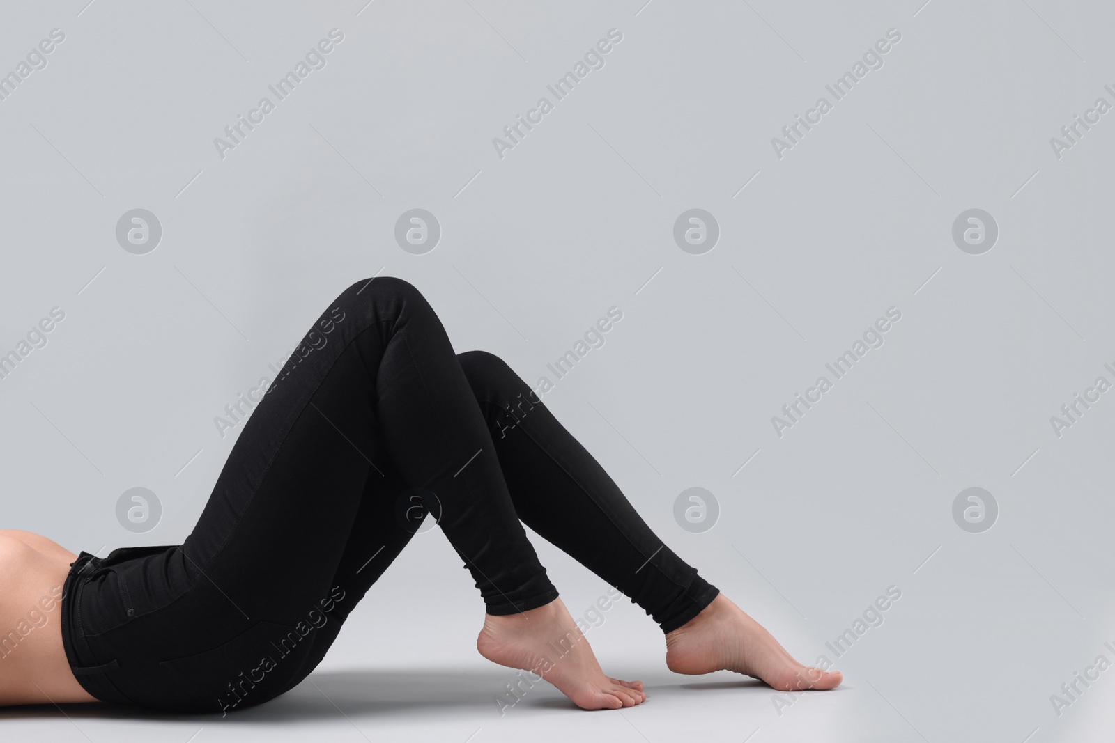 Photo of Woman wearing stylish black jeans on light gray background, closeup. Space for text