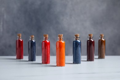 Photo of Glass bottles with different food coloring on white marble table