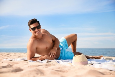 Happy man with slim body resting on beach