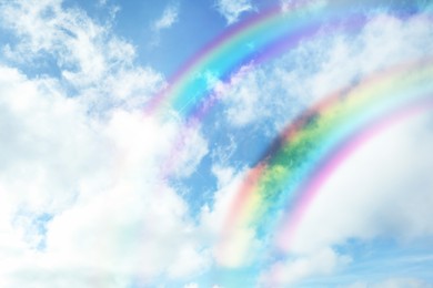 Image of Beautiful view of bright rainbows in blue sky on sunny day