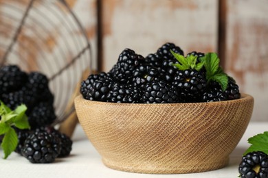 Photo of Bowl with fresh ripe blackberries on white wooden table, closeup