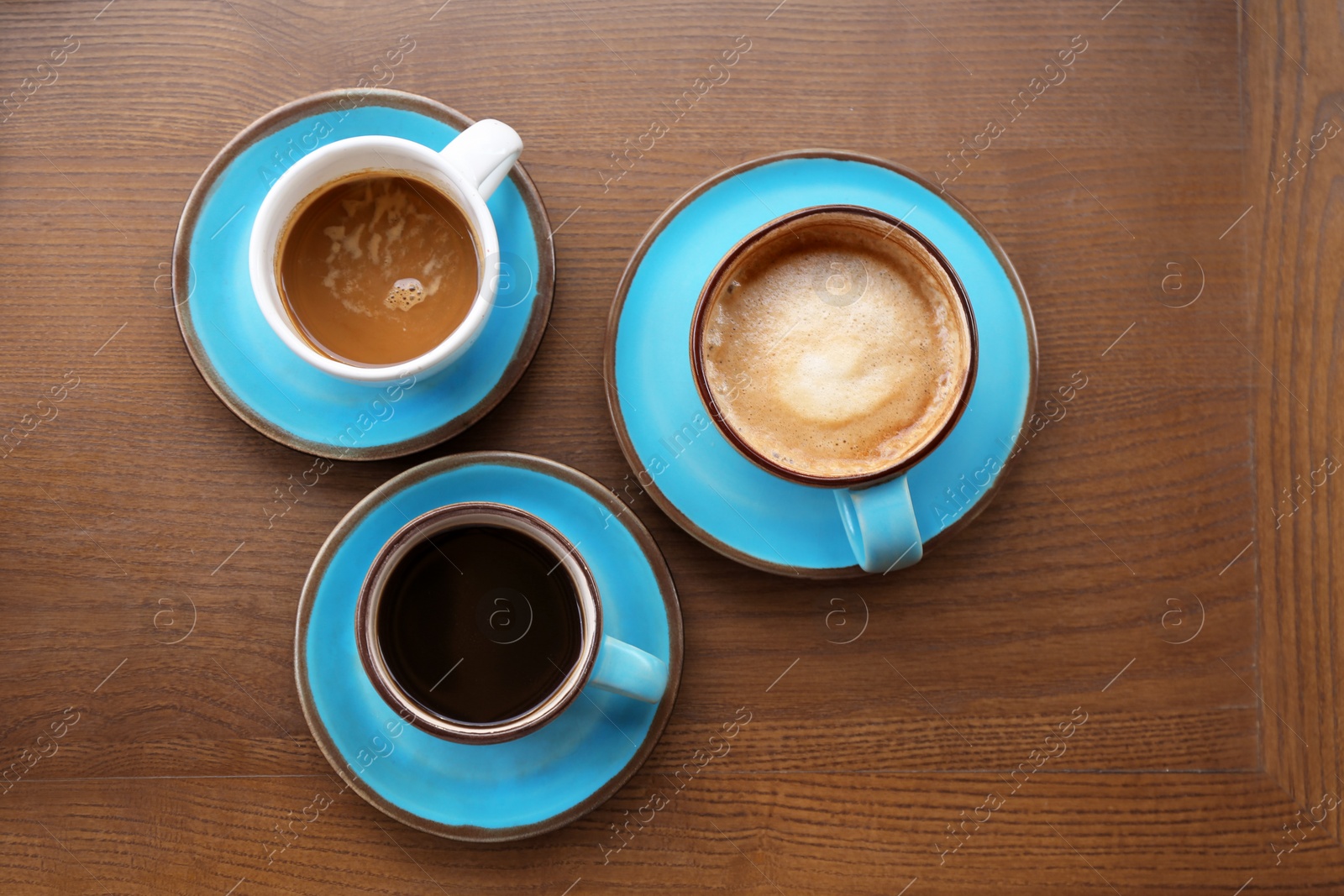 Photo of Cups of fresh aromatic coffee on wooden table, top view