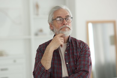 Portrait of thoughtful grandpa with glasses indoors