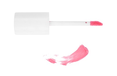 Photo of Stroke of pink lip gloss and applicator isolated on white, top view