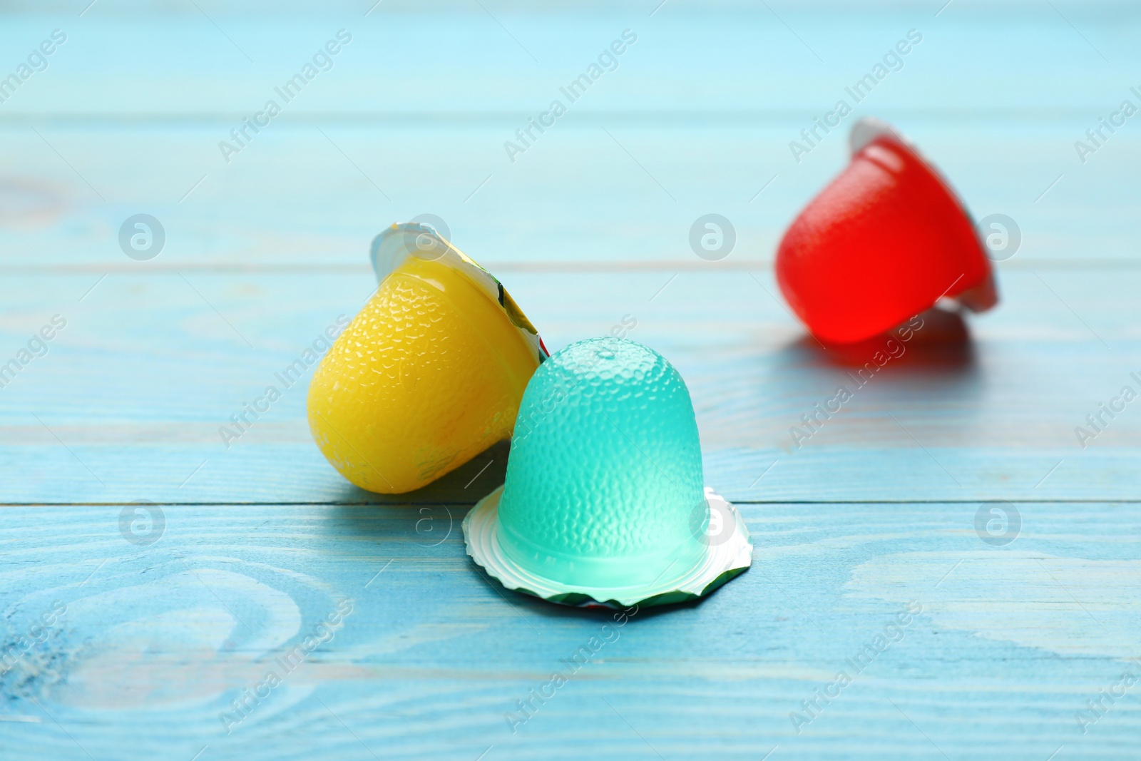 Photo of Tasty bright jelly cups on light blue wooden table