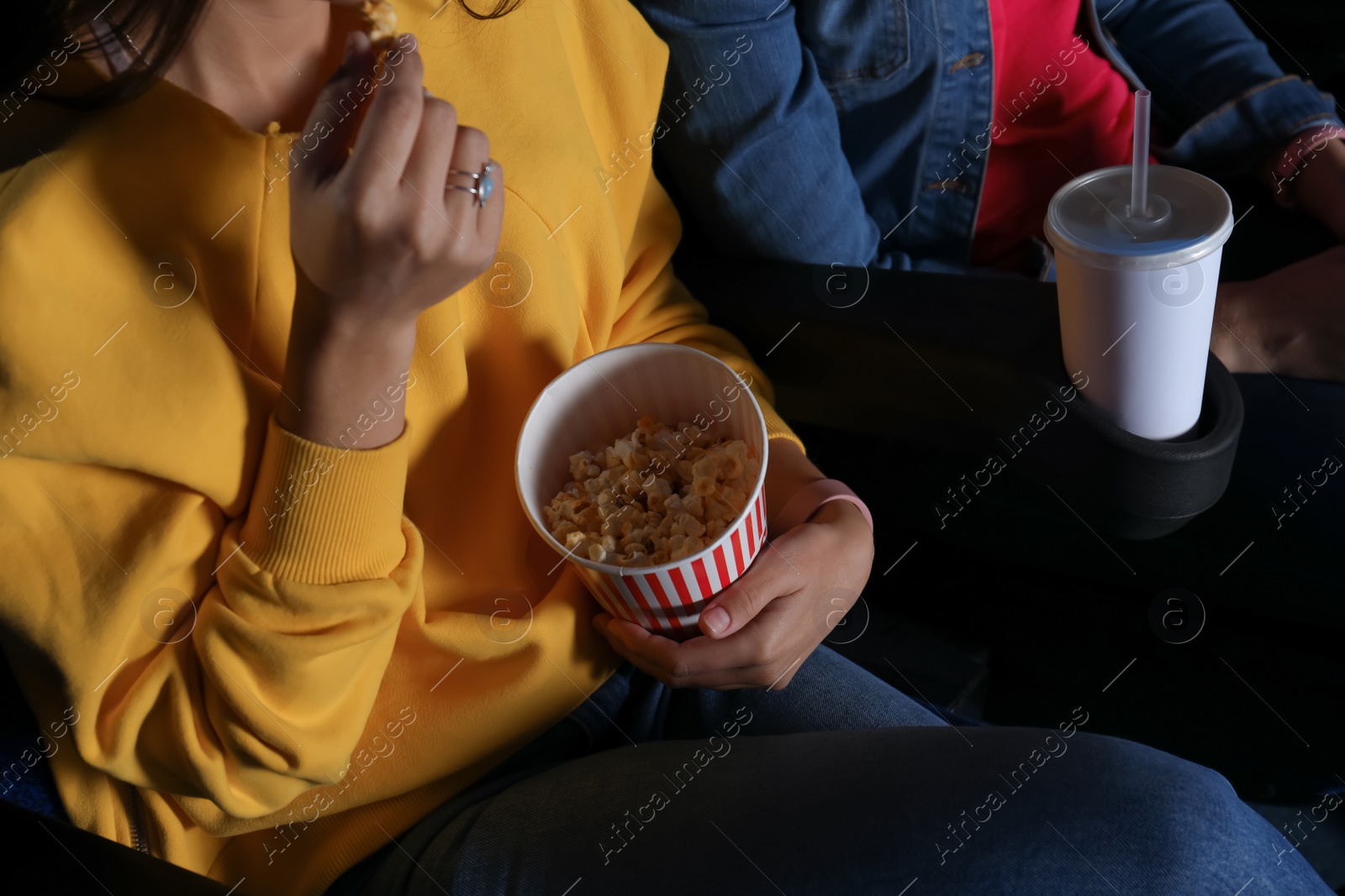 Photo of Young woman with popcorn watching movie in cinema, closeup