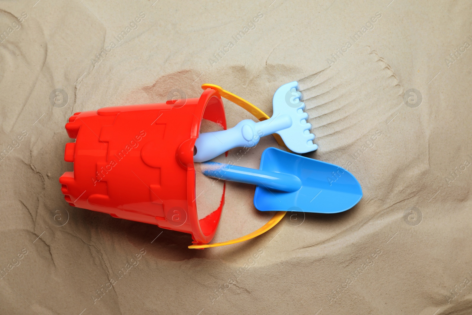 Photo of Plastic toy set with shovel on sand, flat lay