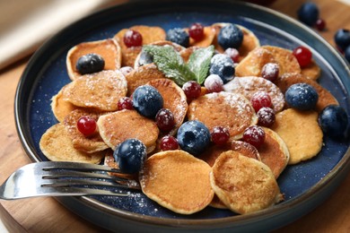 Photo of Cereal pancakes with berries on wooden board, closeup