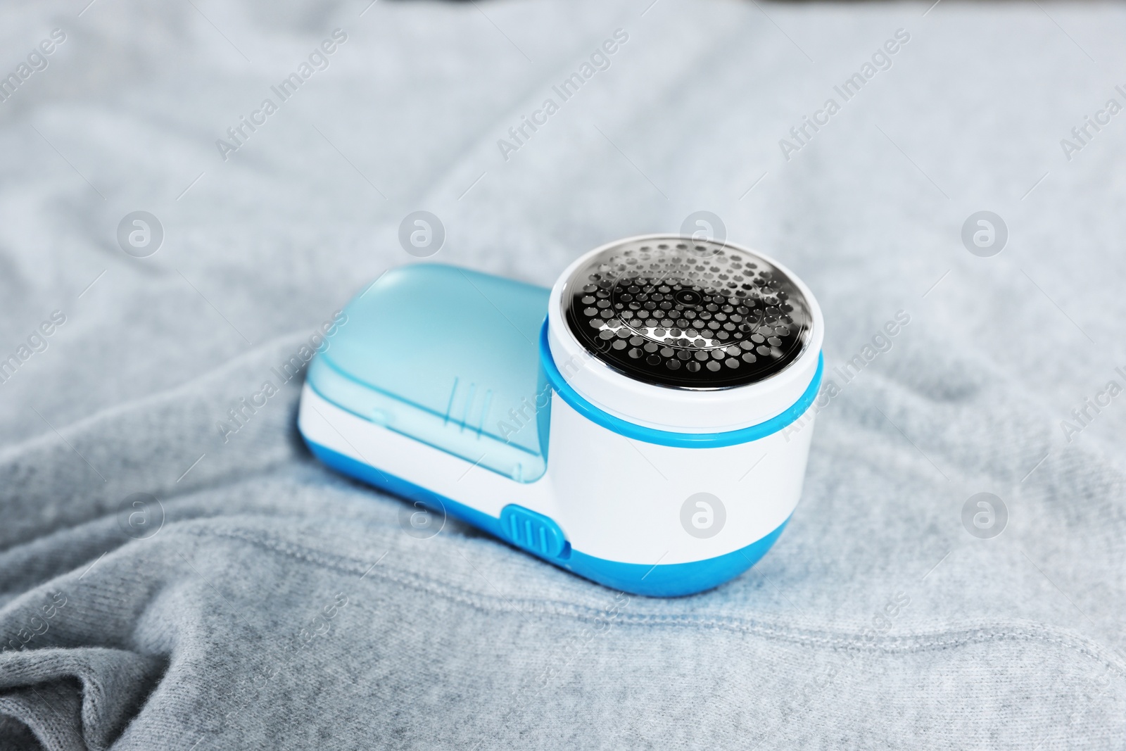 Photo of Modern fabric shaver on light grey cloth, closeup