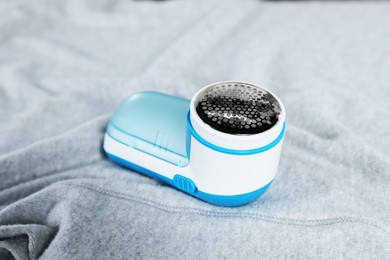 Modern fabric shaver on light grey cloth, closeup