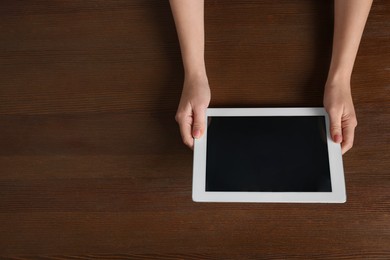 Photo of Woman working with tablet at wooden table, top view. Space for text