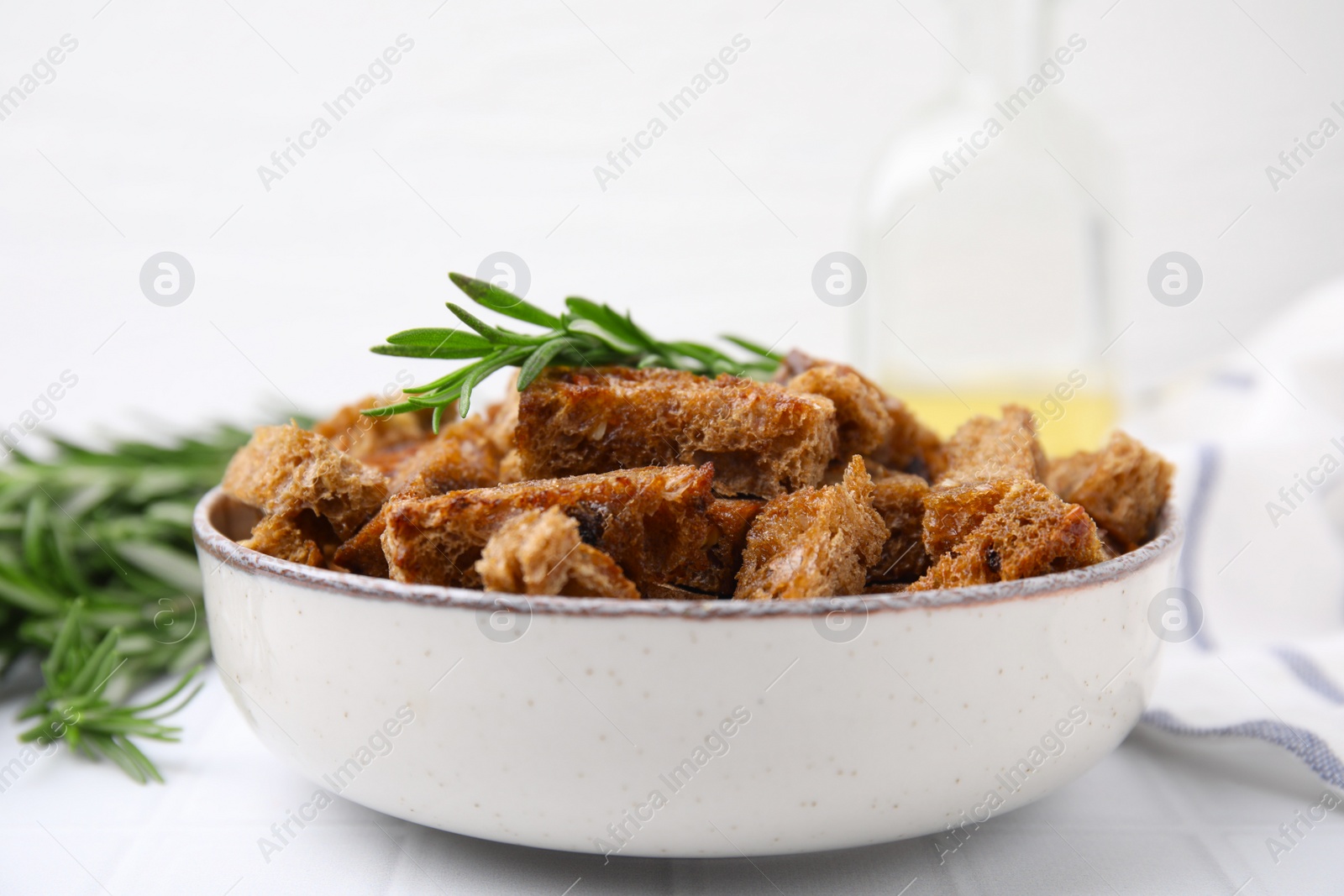 Photo of Crispy rusks with rosemary on white tiled table, closeup