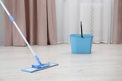 Photo of Cleaning dirty wooden floor with mop indoors