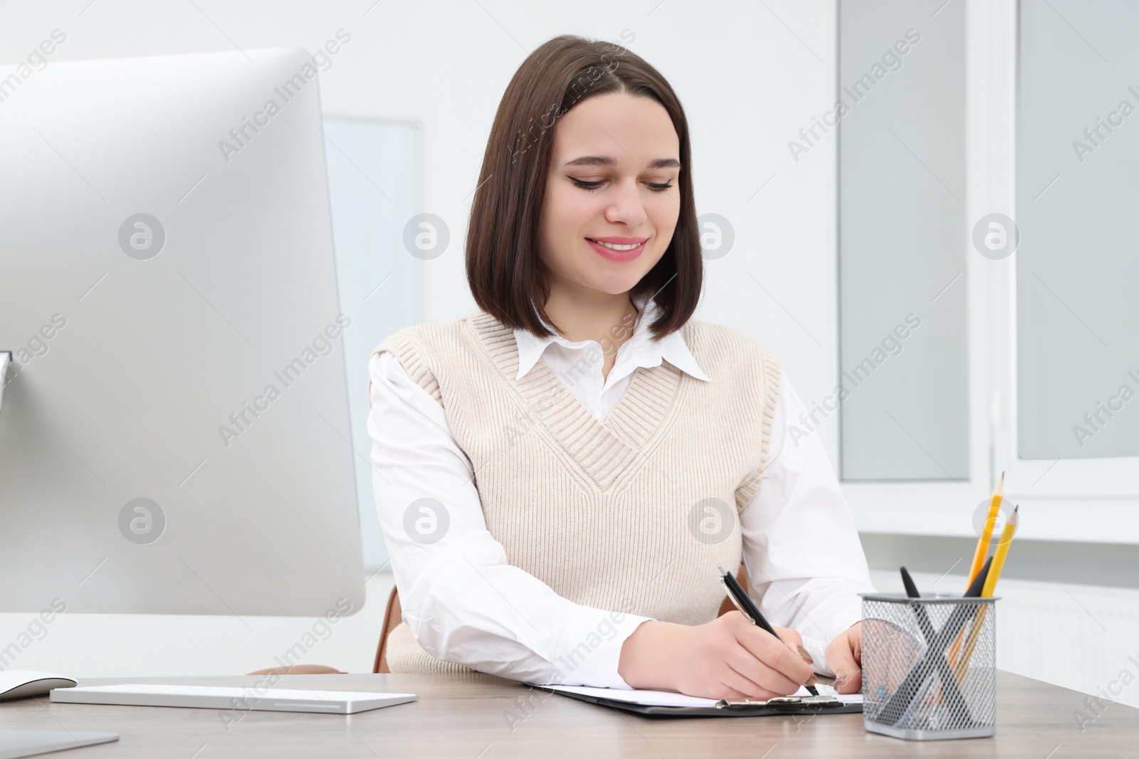 Photo of Happy young intern working at table in modern office