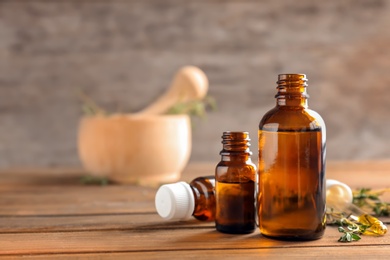 Bottles of essential oil with thyme on wooden table