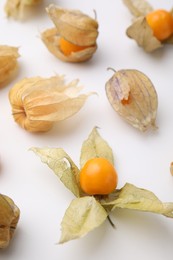 Photo of Ripe physalis fruits with calyxes on white background, closeup