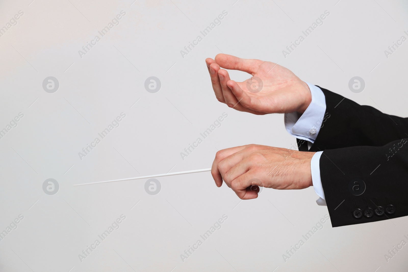 Photo of Professional conductor with baton on light grey background, closeup. Space for text