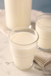 Photo of Glasses of fresh milk on white marble table, closeup