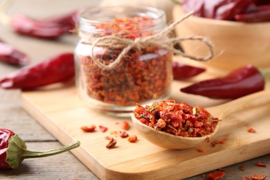 Photo of Chili pepper flakes and pods on wooden table, closeup