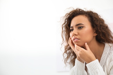 Photo of African-American woman suffering from tooth ache on white background. Space for text