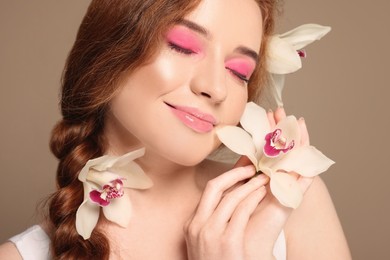 Portrait of beautiful happy woman posing with lilies on beige background, closeup