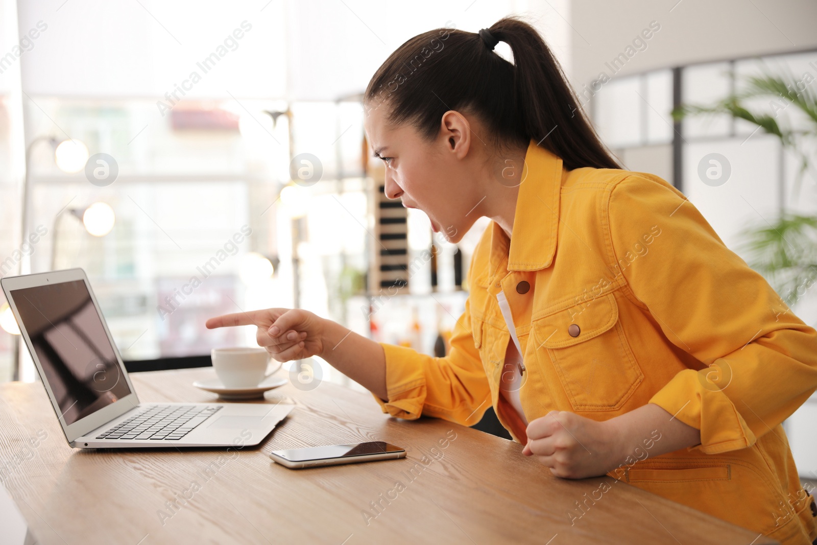 Photo of Emotional young woman working on laptop in office. Online hate concept