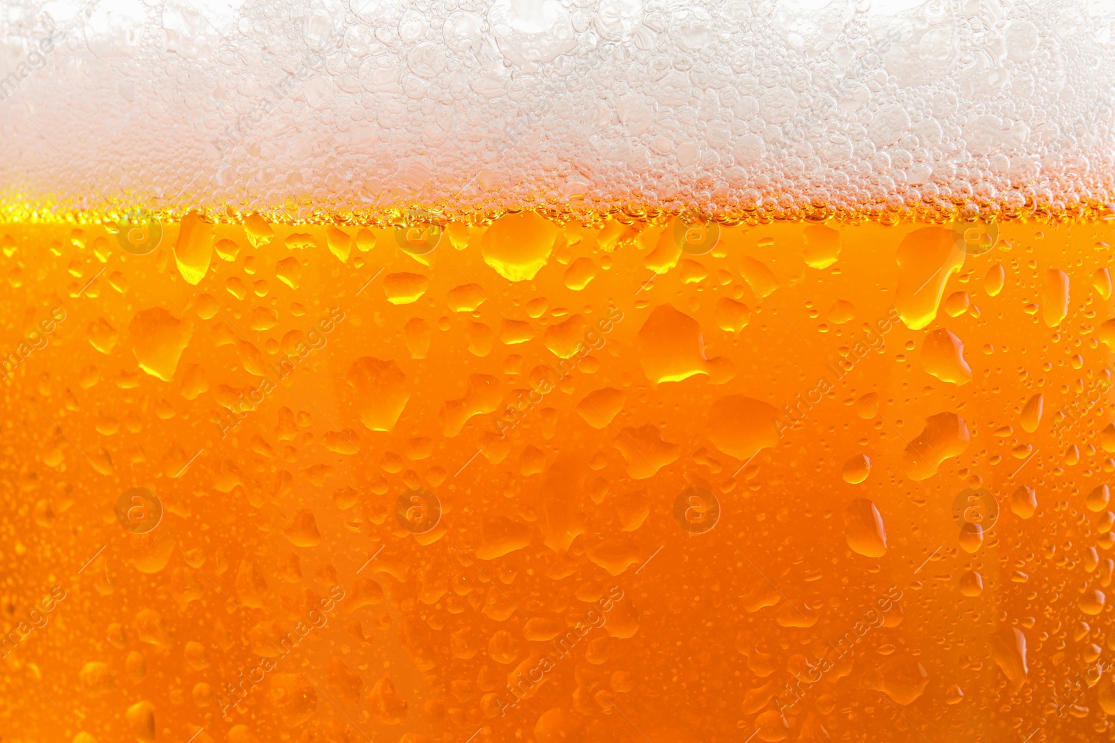 Photo of Glass of tasty cold beer with foam and condensation drops as background, closeup