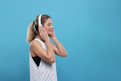 Photo of Sportswoman with headphones on light blue background, space for text