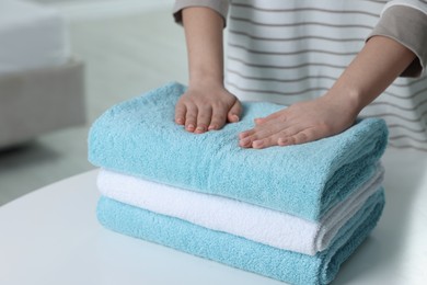 Woman touching soft light blue towel indoors, closeup