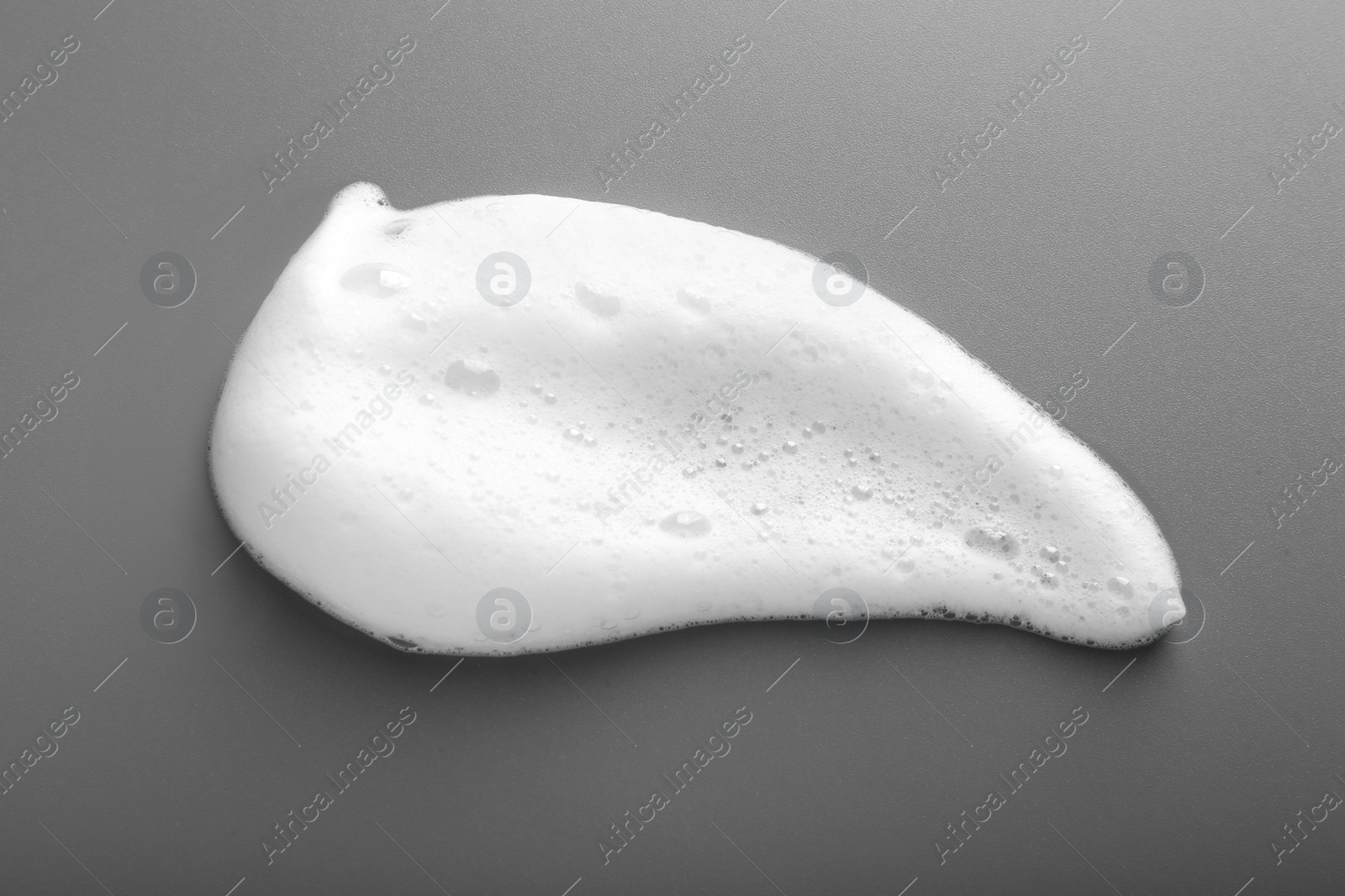 Photo of White foam with bubbles on grey background, top view