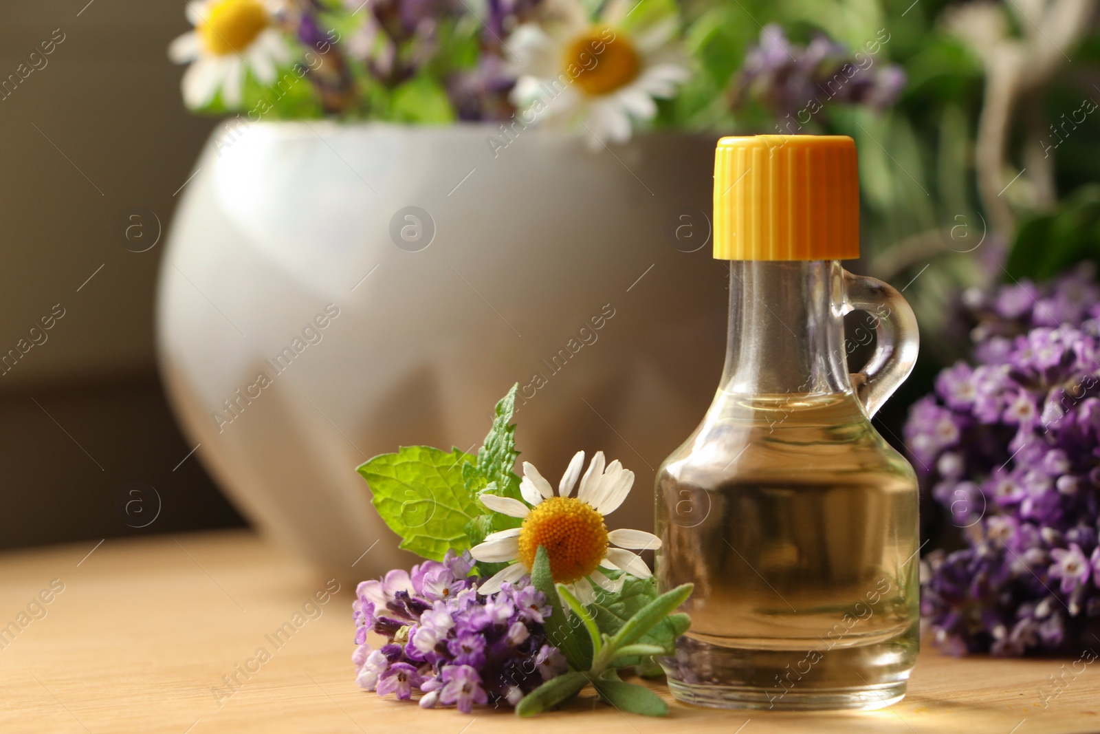 Photo of Bottle of natural lavender essential oil near mortar with flowers on wooden table, closeup. Space for text