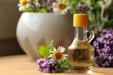 Bottle of natural lavender essential oil near mortar with flowers on wooden table, closeup. Space for text