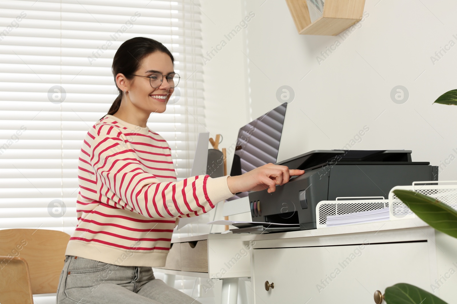 Photo of Woman using modern printer at workplace indoors