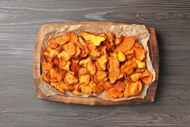 Photo of Tray with sweet potato chips on wooden table, top view