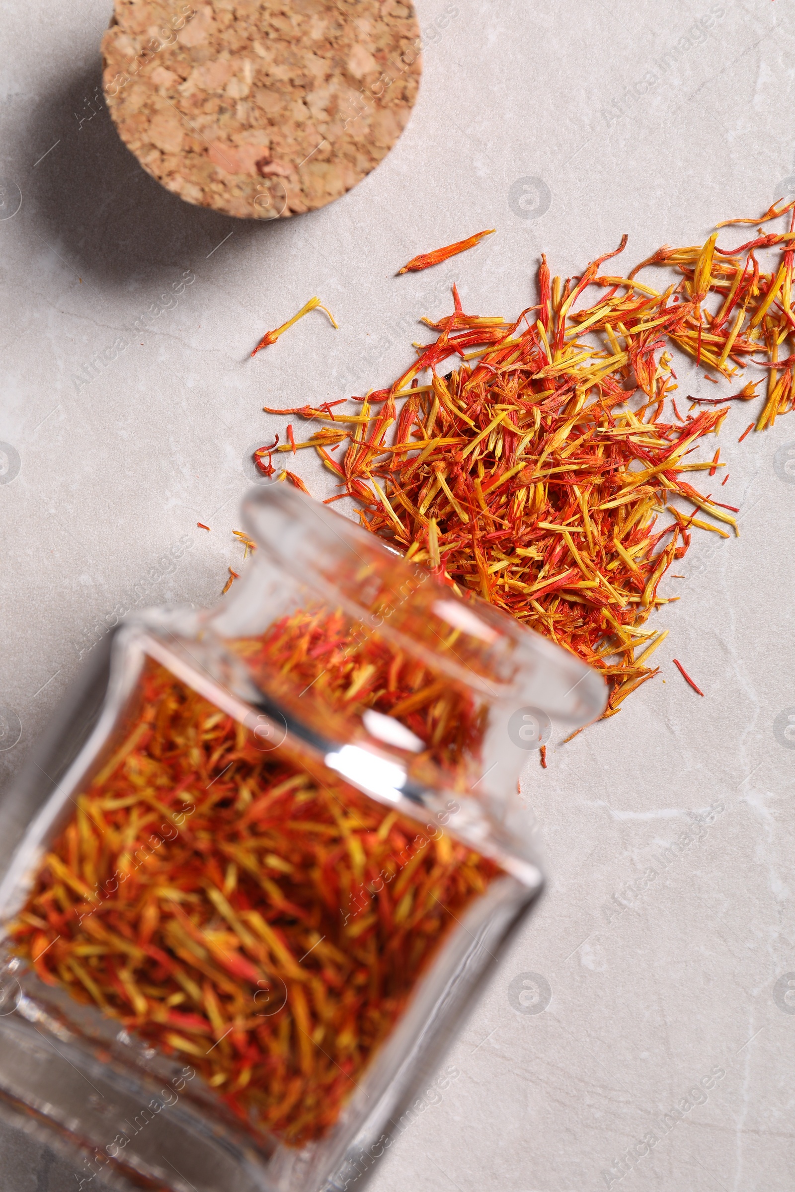 Photo of Aromatic saffron, glass jar and lid on light gray table, flat lay