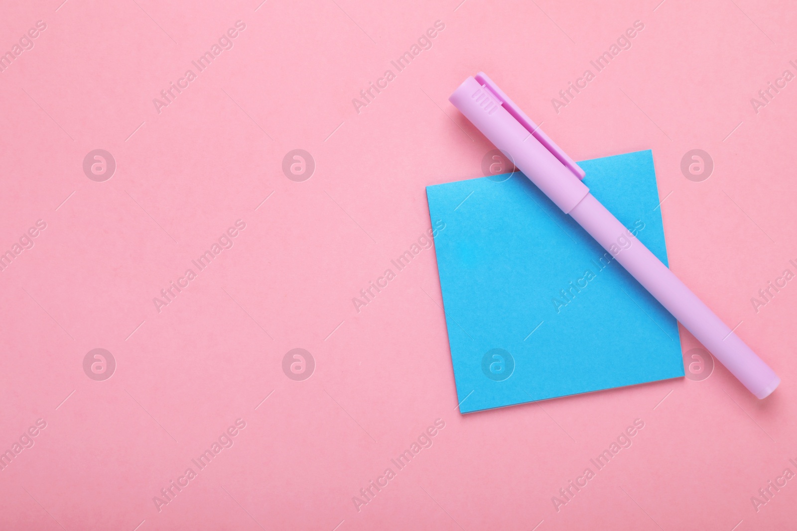 Photo of Paper note and purple marker on pink background, top view. Space for text